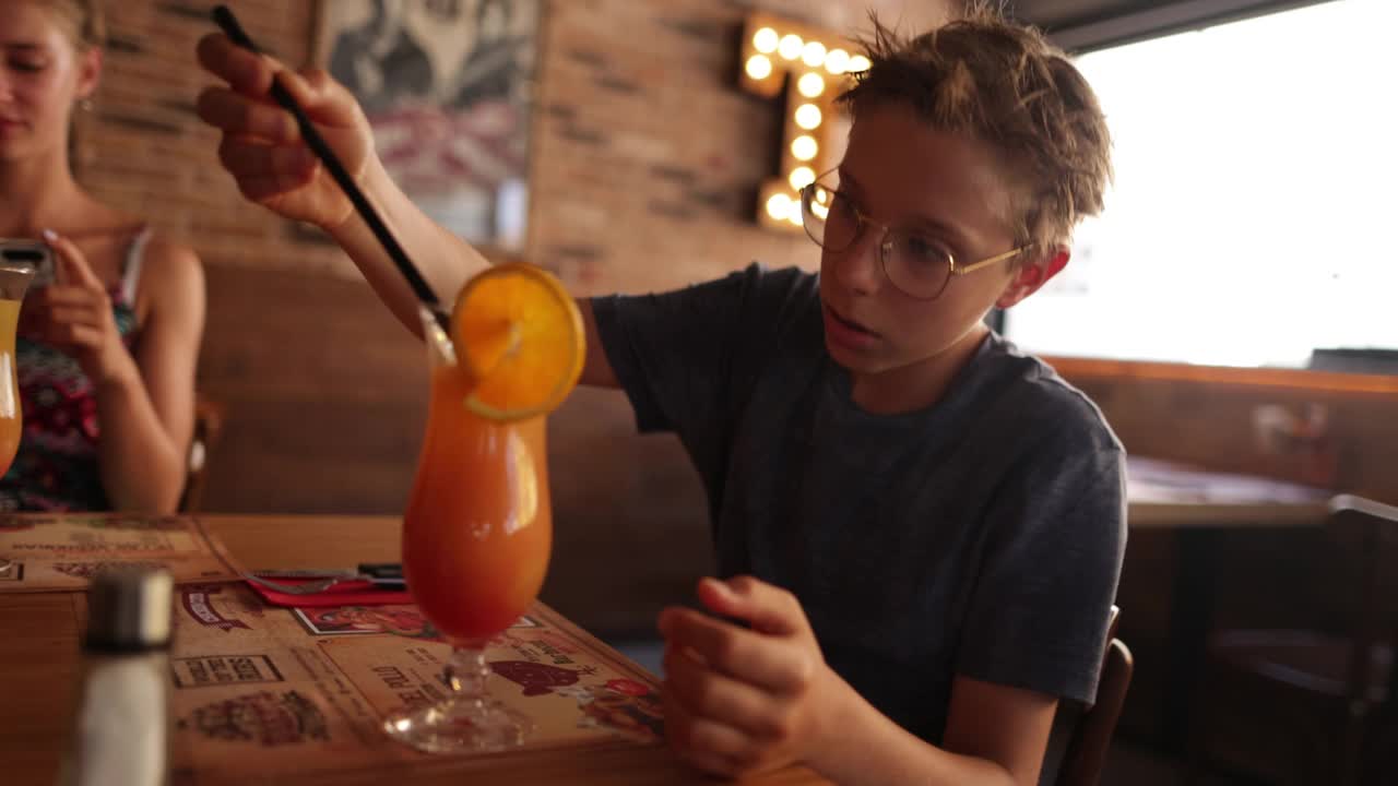 一个十几岁的男孩在餐厅喝果汁视频素材
