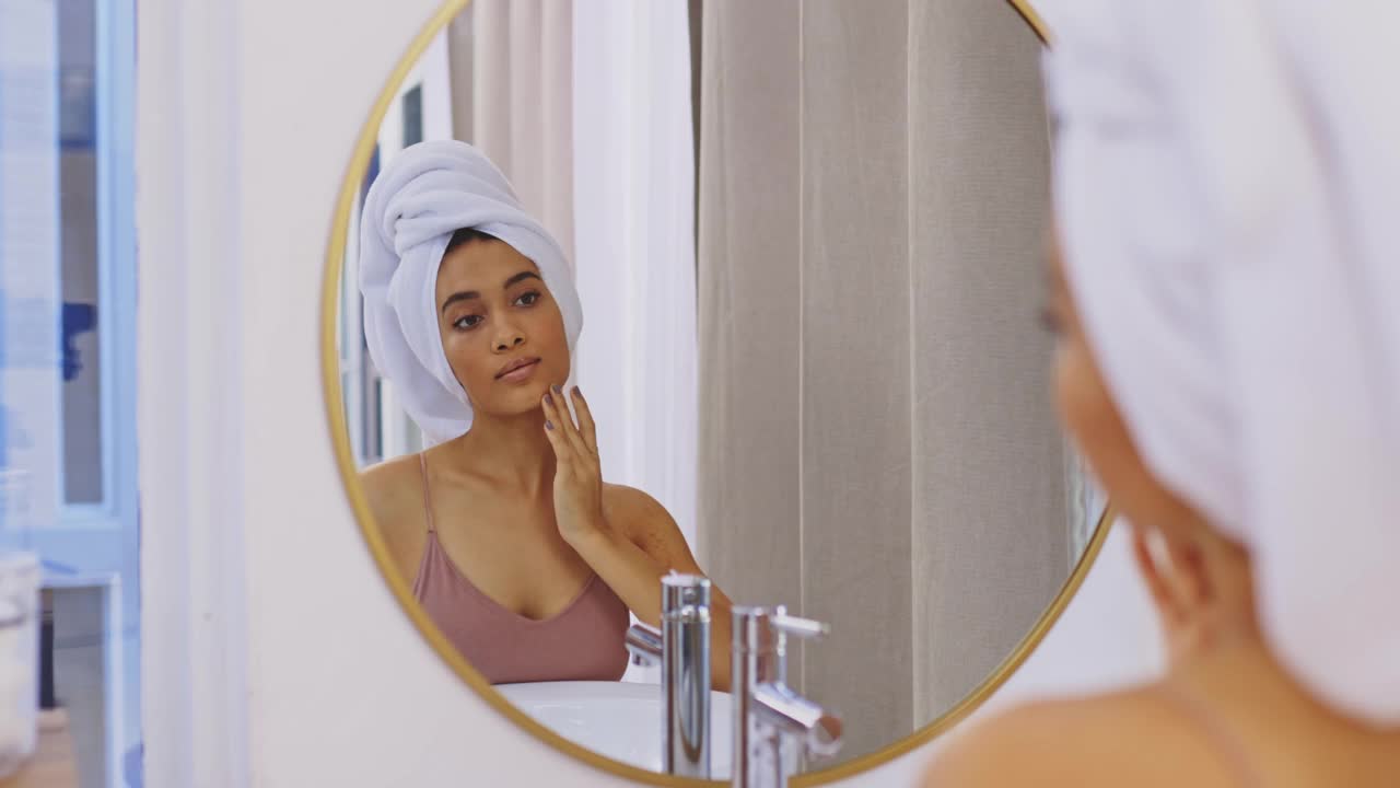 4k视频，一个迷人的年轻女人在浴室镜子里审视自己的脸视频下载