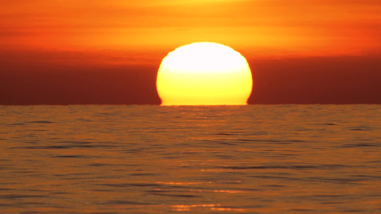大红热太阳在暖空气扭曲在海洋地平线，日落在海上，大升起的太阳与云。特写镜头长焦镜头。旅行，开始，自然的概念视频素材