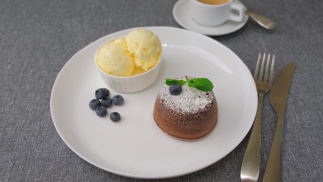 熔岩蛋糕是一种巧克力方旦糖蛋糕，里面有香草冰淇淋、蓝莓、薄荷和咖啡。传统的法国糕点。女人的削减视频素材