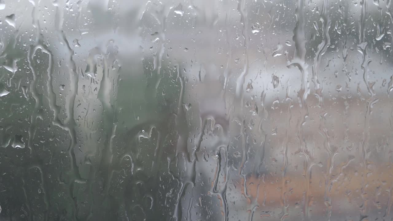 雨季，城市大雨倾盆，水珠落在玻璃表面，特写湿窗作为纹理或背景视频素材