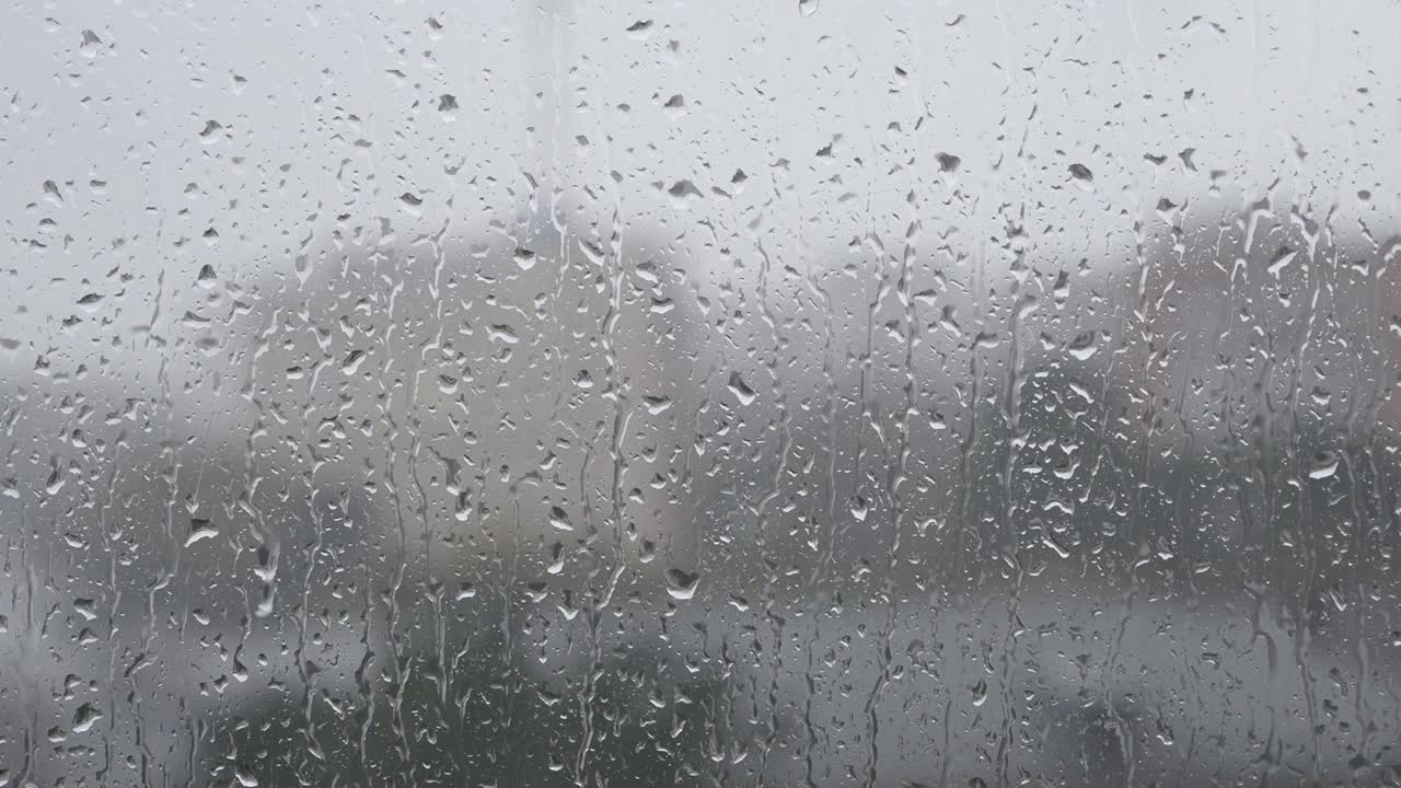 雨季，城市大雨倾盆，水珠落在玻璃表面，特写湿窗作为纹理或背景视频素材