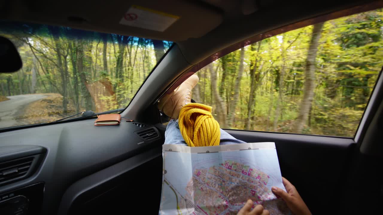 一名将双腿伸出车窗外的女子在森林里看地图视频下载