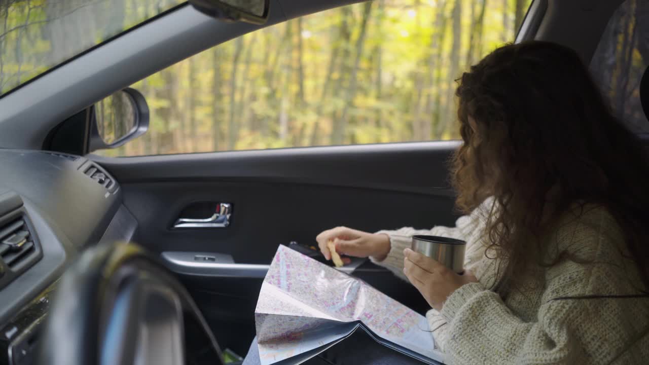 森林路上的一名妇女在车里看地图视频素材