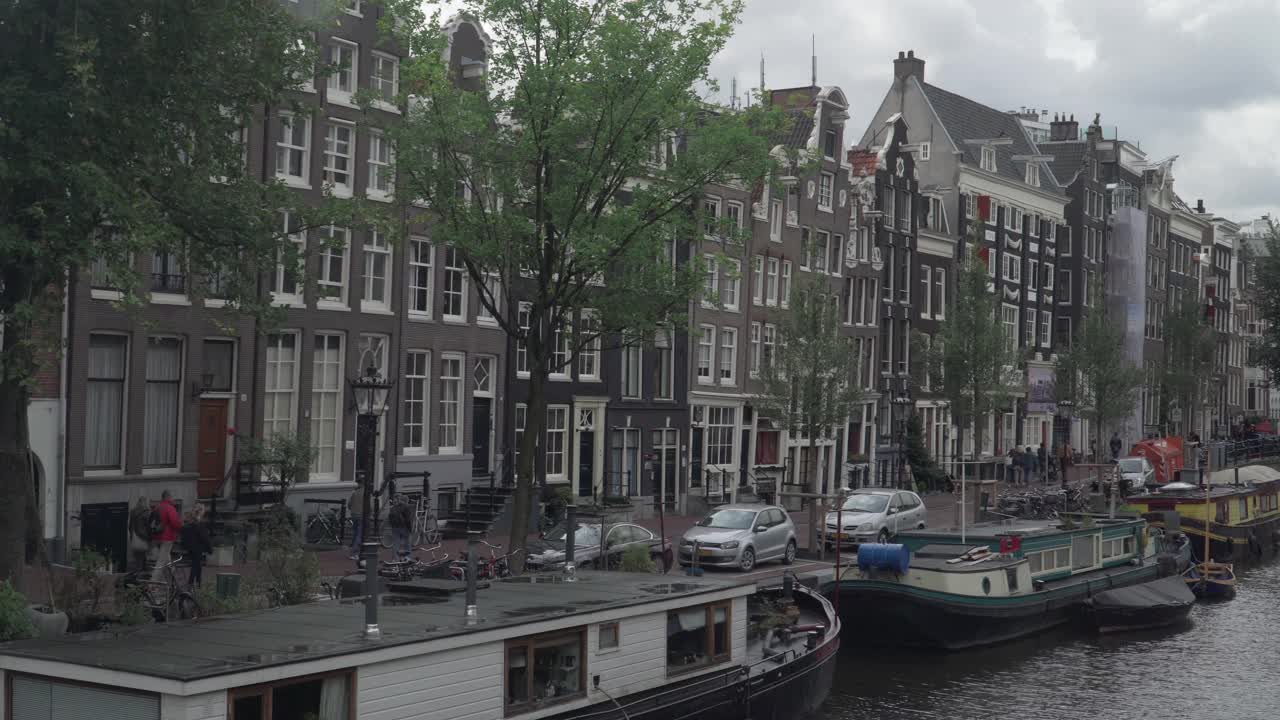 沿着阿姆斯特丹运河的步行街，在恶劣的天气下，一艘船，平移视野视频素材