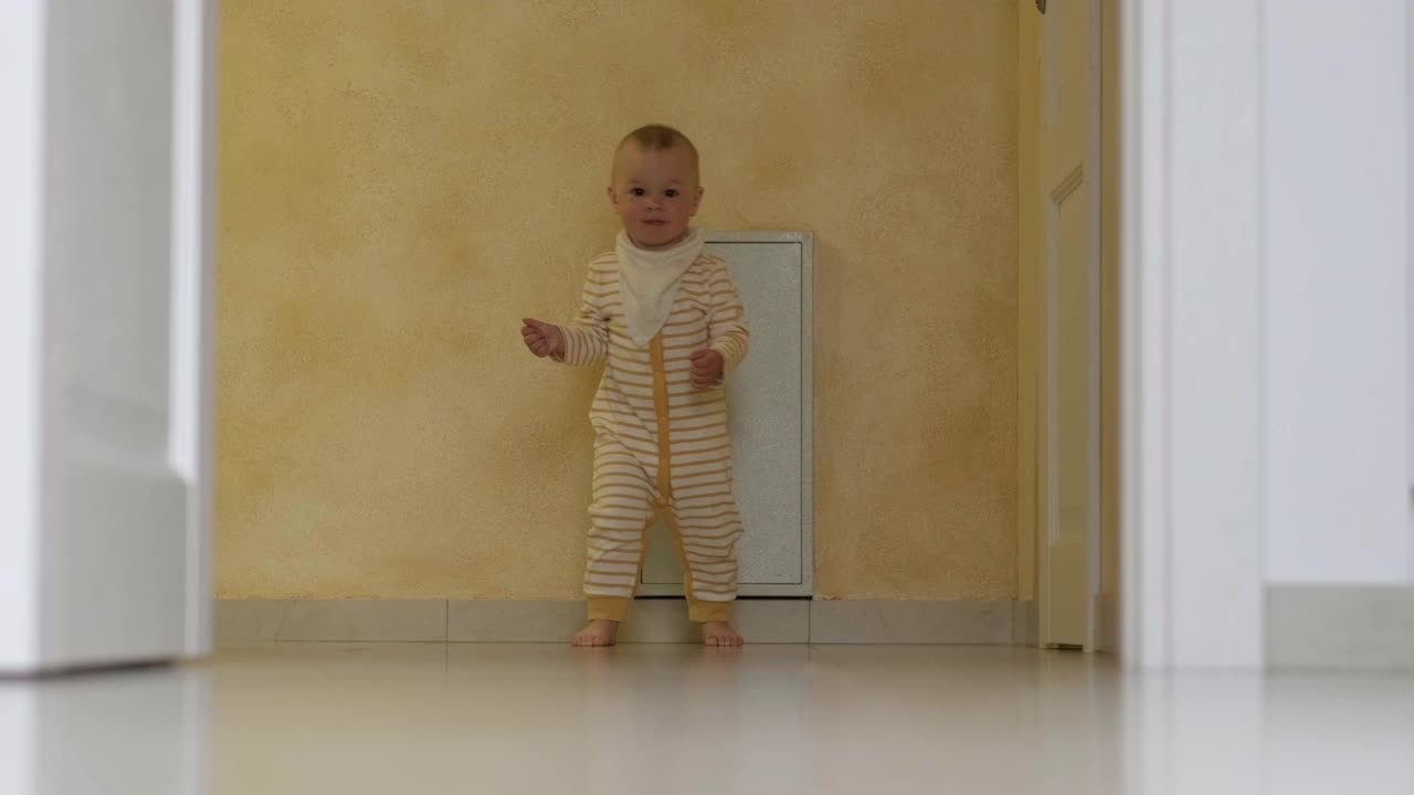 宝宝迈出了第一步。小女孩或小男孩在家里白色的地板上跑着走着。光脚小孩在厨房视频素材