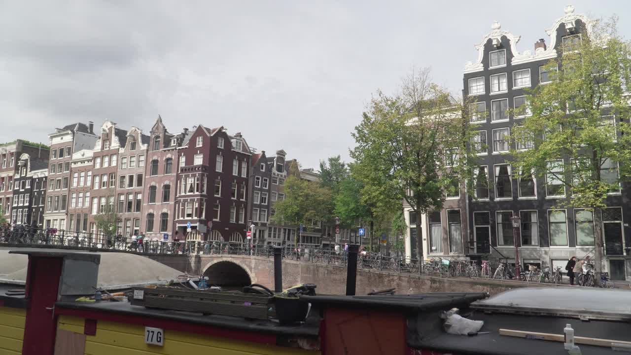 荷兰风格的房子在阿姆斯特丹随着canel与船在恶劣的天气，平移的观点视频素材