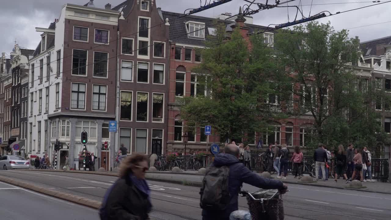 行人和行人在城市里行走，荷兰风格的房子沿着阿姆斯特丹的公路和铁路排成一排，天气恶劣，景色宜人视频素材