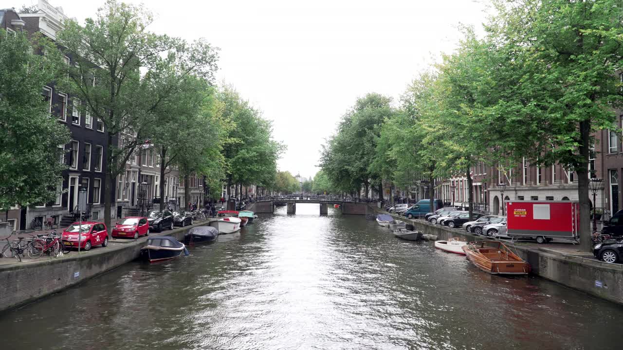 在阿姆斯特丹运河边的步行街桥，在恶劣的天气里有一艘船视频素材