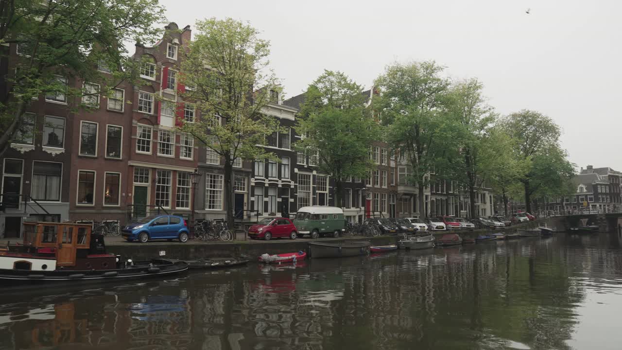 荷兰风格的房子沿着运河和船在阿姆斯特丹在恶劣的天气，平移的观点视频素材