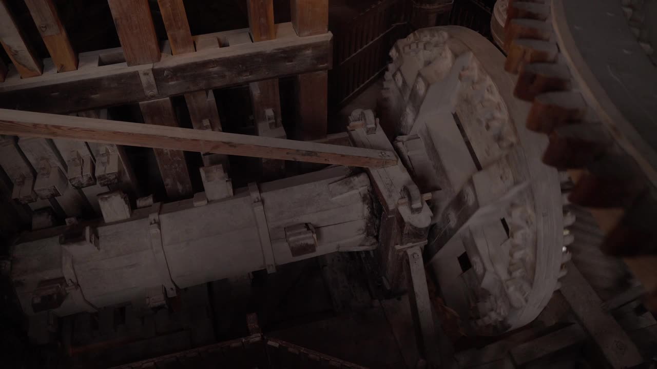 荷兰风车内部与传统自动粉碎装置内的人造齿轮，在恶劣天气下进行粉碎，木质结构的滚动和研磨，高角度平移视图。视频下载