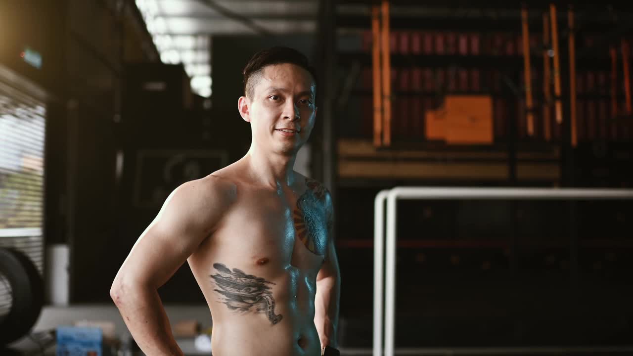 在健身俱乐部，亚洲华人男性健美教练赤裸上身的肖像照视频下载
