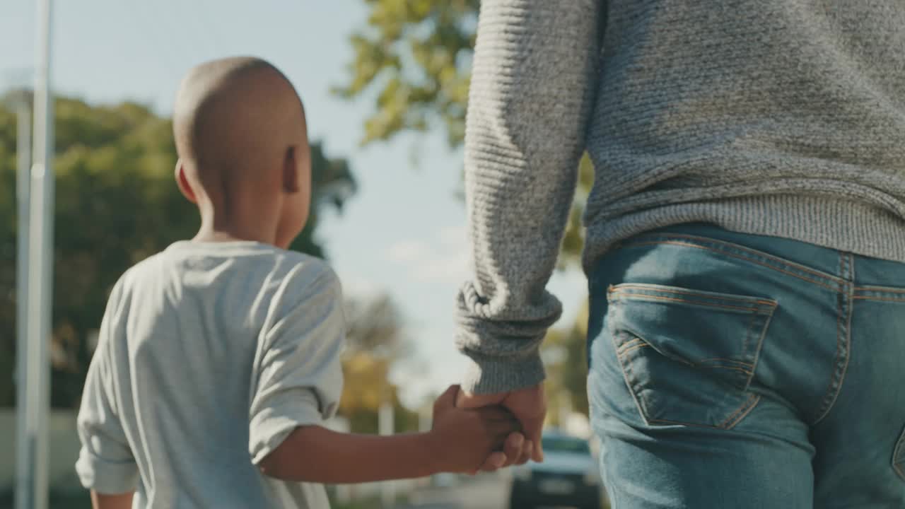 一段4k视频显示一名面目全非的男子和他儿子手拉手走在外面视频素材
