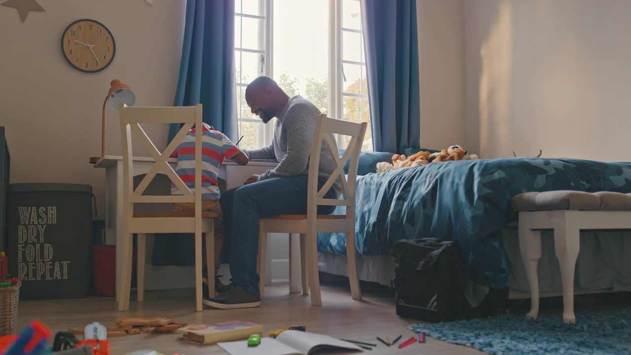 一段4k视频记录了一个英俊成熟的男人在卧室帮儿子做作业的时候和他击掌视频素材