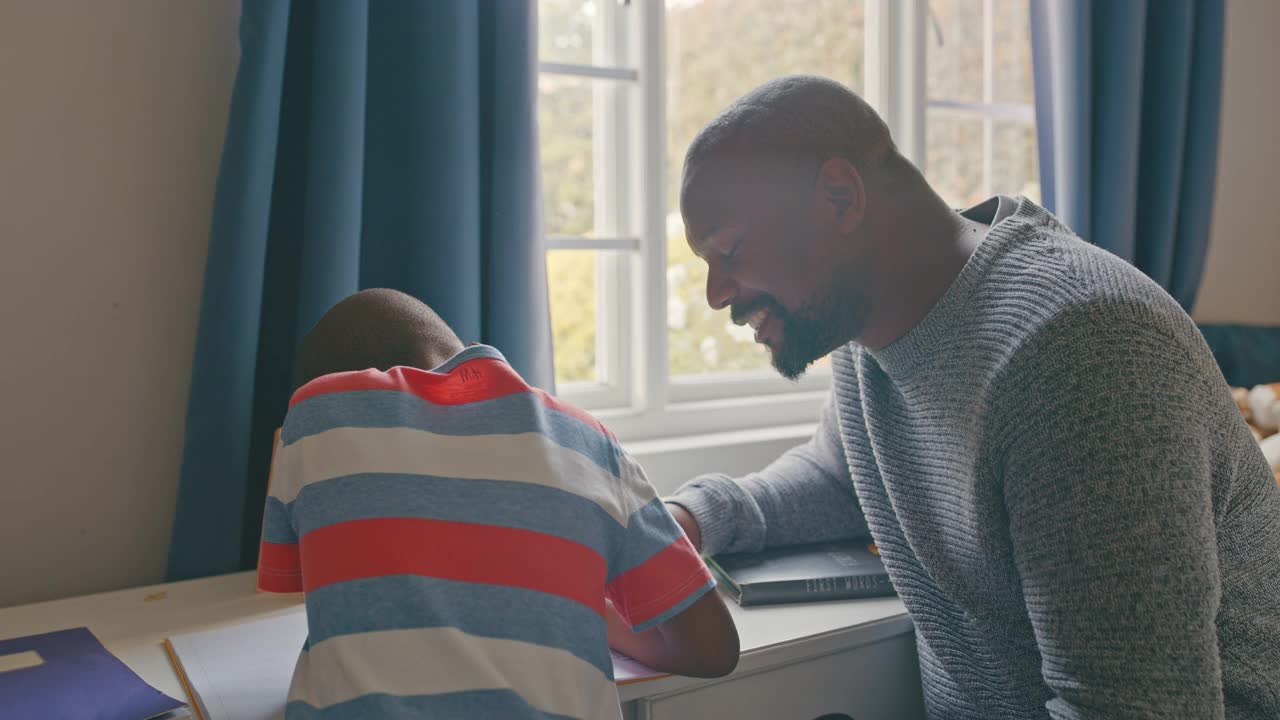 一个帅气成熟的男人在卧室帮儿子做作业的4k视频视频素材