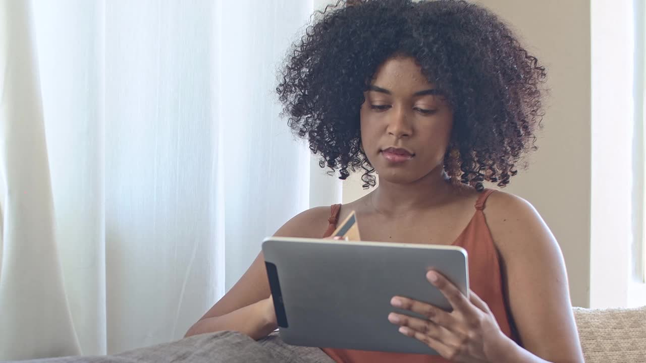 一段4k视频显示一名年轻女子用她的借记卡用她的电子平板电脑在线购物视频素材