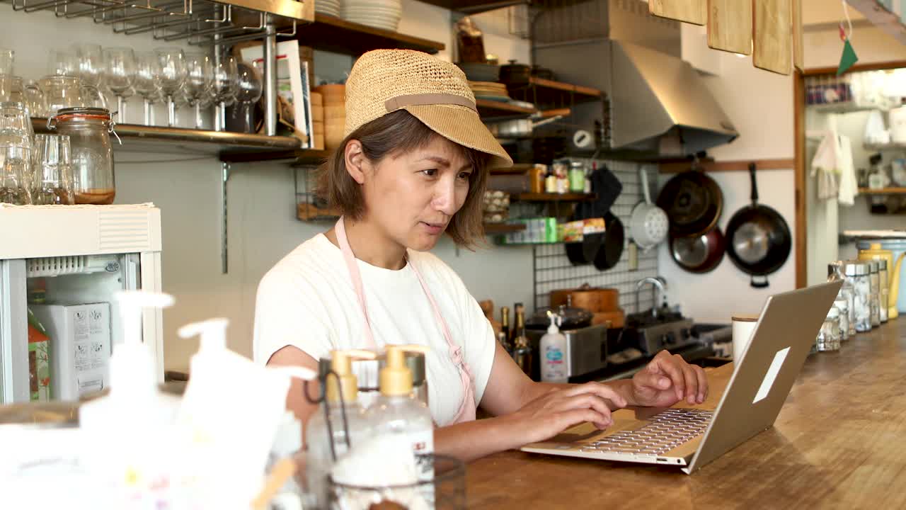一位素食餐厅的女老板独自呆在餐厅里用笔记本电脑工作视频下载