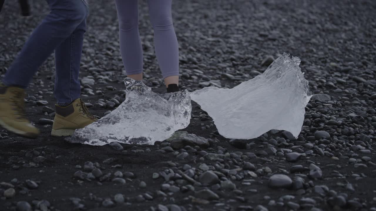 在冰岛的海滩上，一名男子举起大块的冰给女人看视频下载