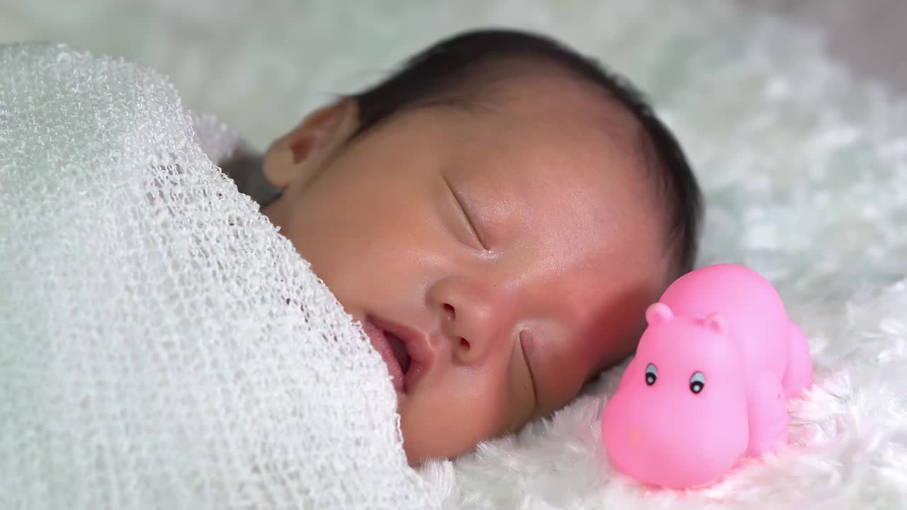新生婴儿睡在河马橡胶玩具旁边视频素材
