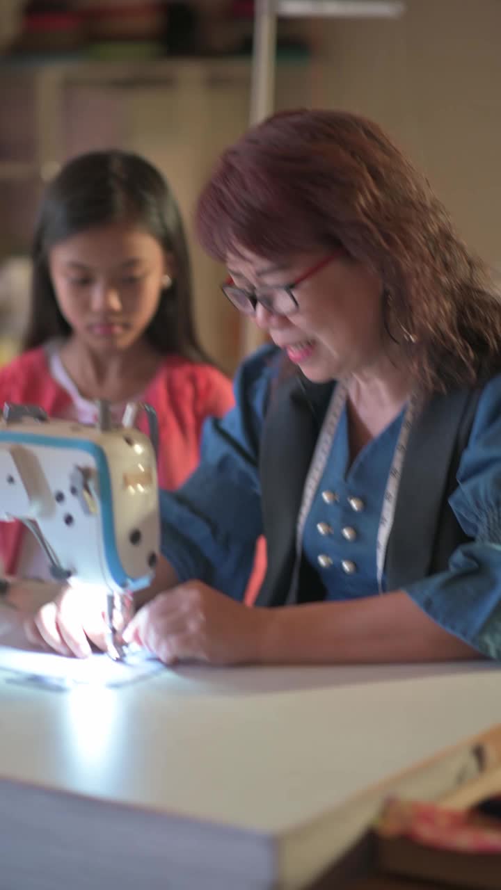 一位亚洲华裔奶奶在她的工作室用缝纫机给她的孙女缝制面料保护口罩视频下载