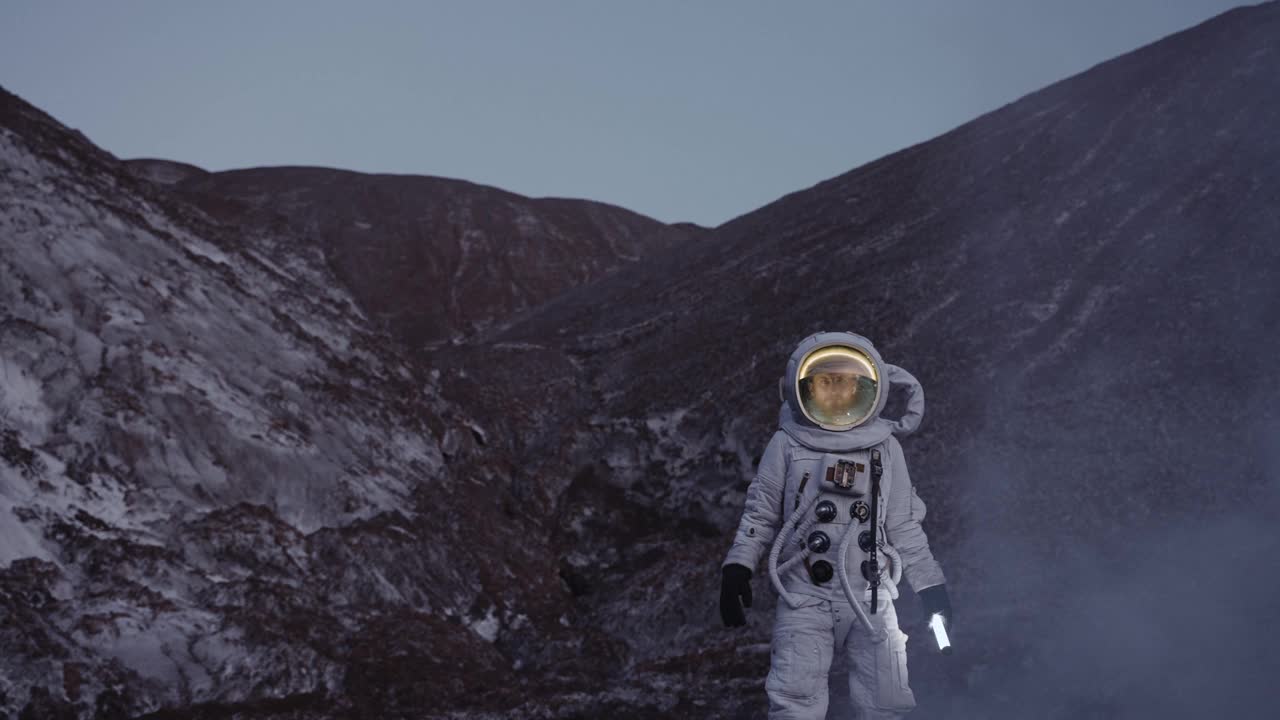 黄昏时分，一名宇航员提着灯笼穿过一团蒸汽从山上走下来视频素材