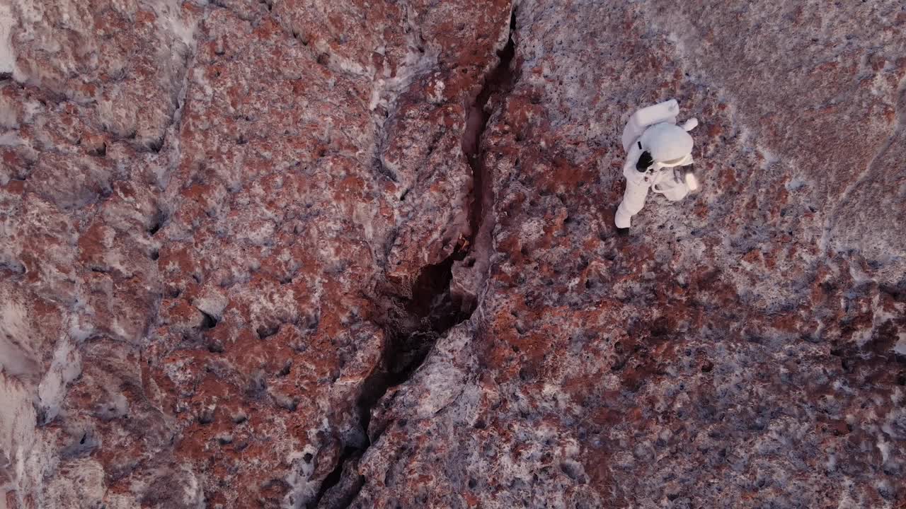 宇航员提着灯笼小心翼翼地从悬崖上下来。航空摄影视频素材