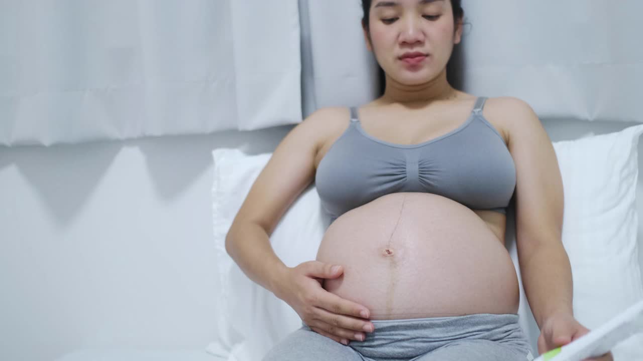 怀孕的夫妇在家里感受到爱和放松。视频下载