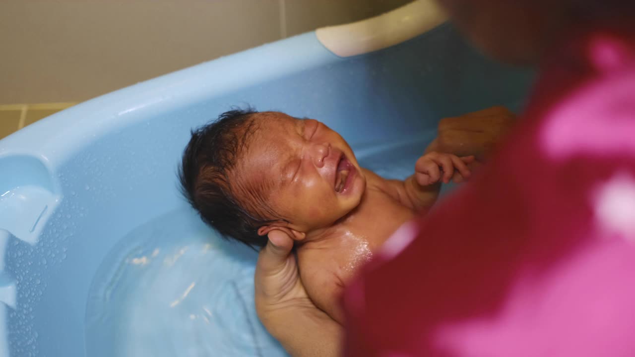 一个刚出生的小婴儿，在妈妈的蓝色浴缸里沐浴视频下载