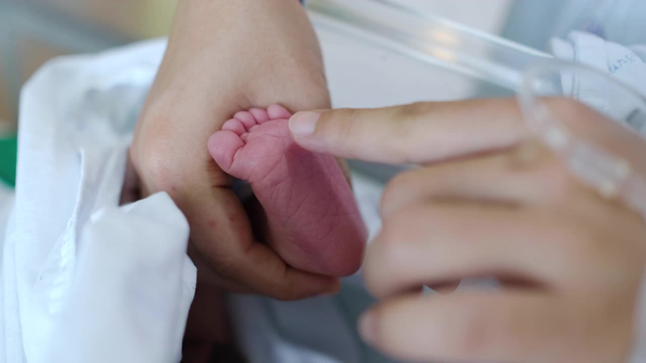 妈妈抱着她刚出生的婴儿的脚视频下载