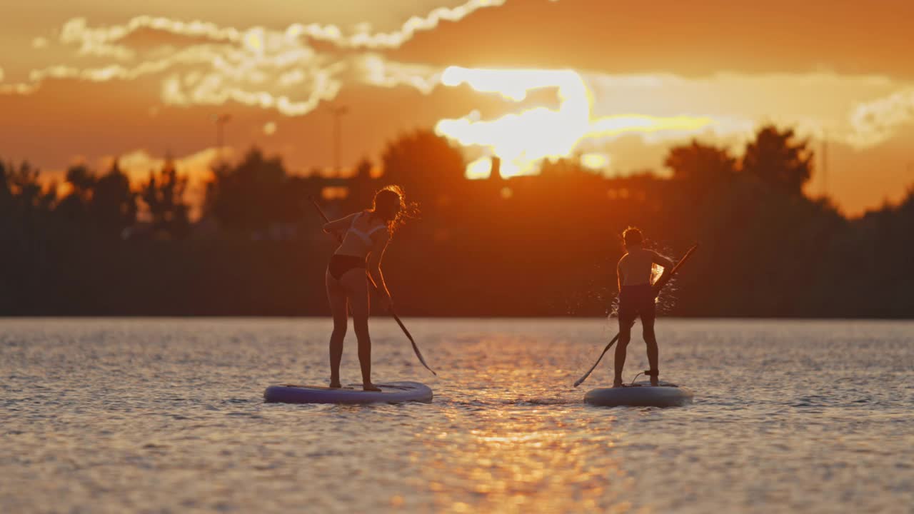 女人和男孩在河上划着桨嬉戏，把水泼到对方身上视频素材