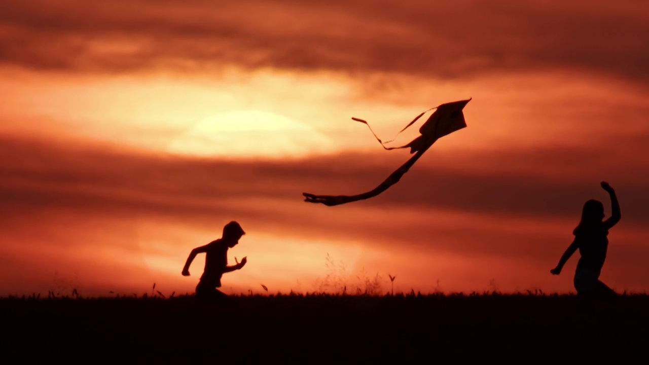 夕阳下兄妹玩风筝的剪影视频素材