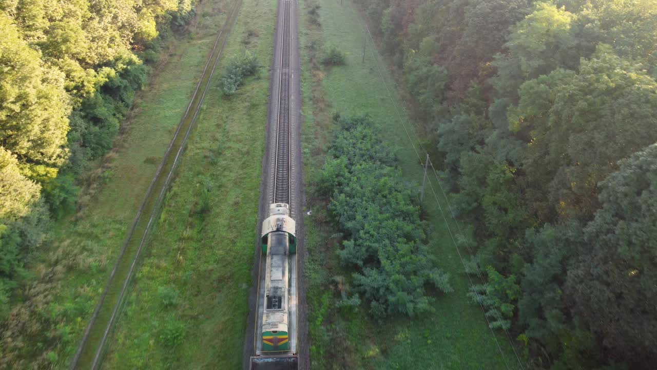 一列柴油火车沿着铁轨穿过森林。鸟瞰图视频下载