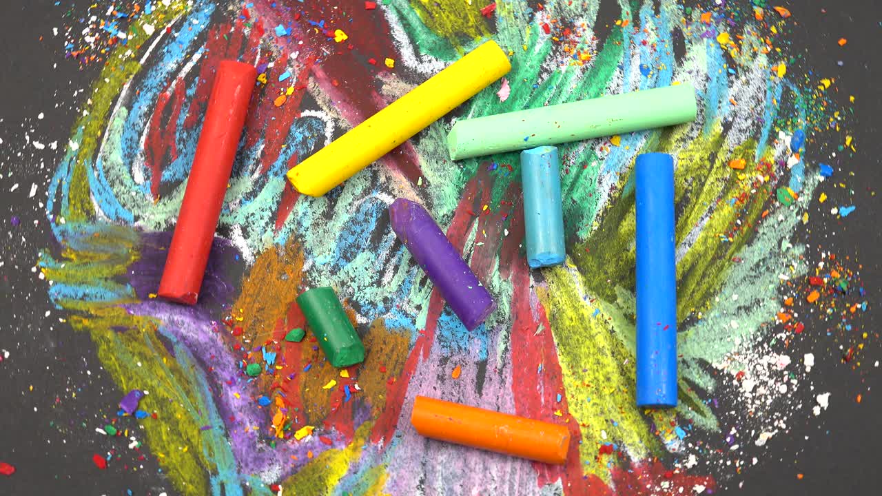 五颜六色的蜡笔躺在他们画的抽象背景上。视频素材