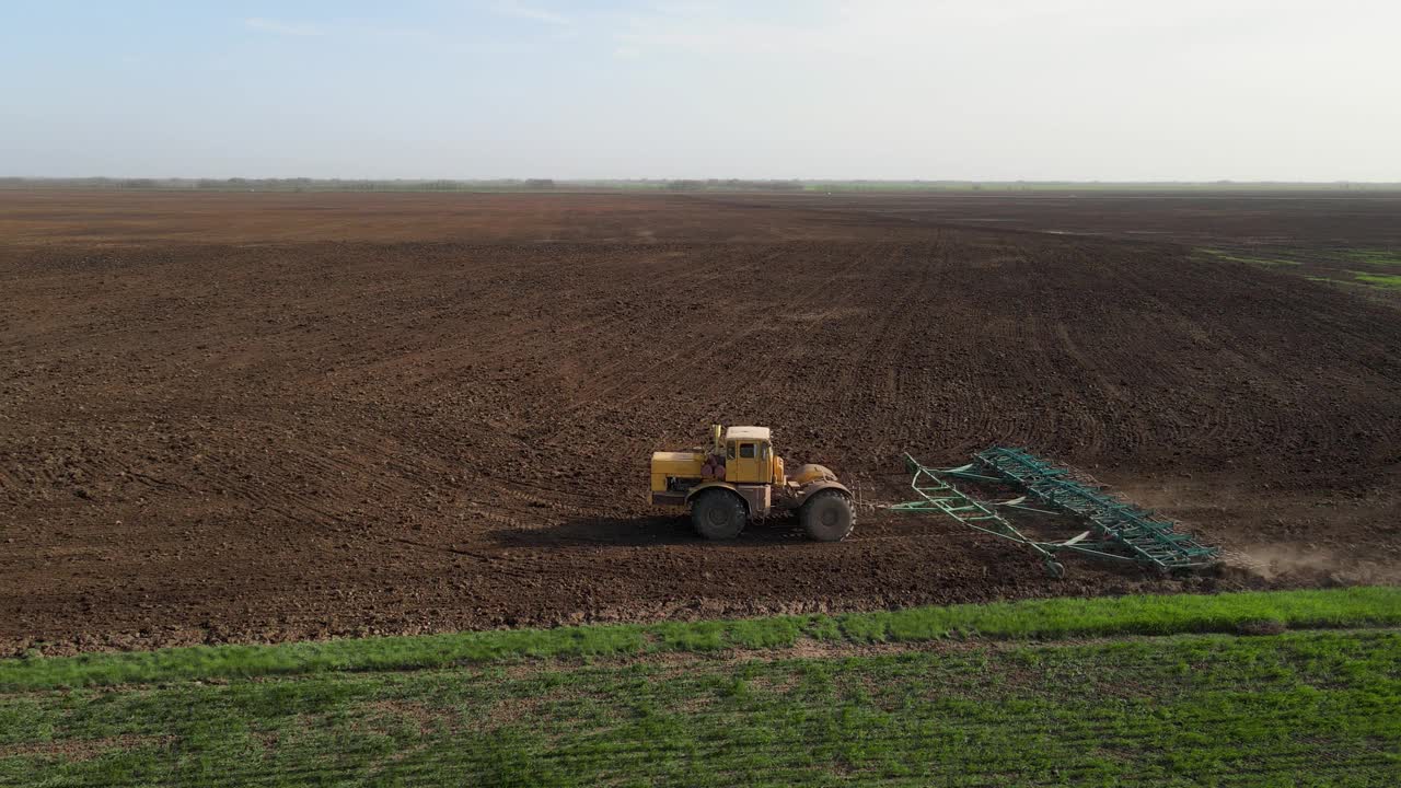 拖拉机用耙子在地里干活，转身离开了。松动地面，保护土壤，平整其表面，准备种植小麦和消灭杂草，无人机射击视频下载