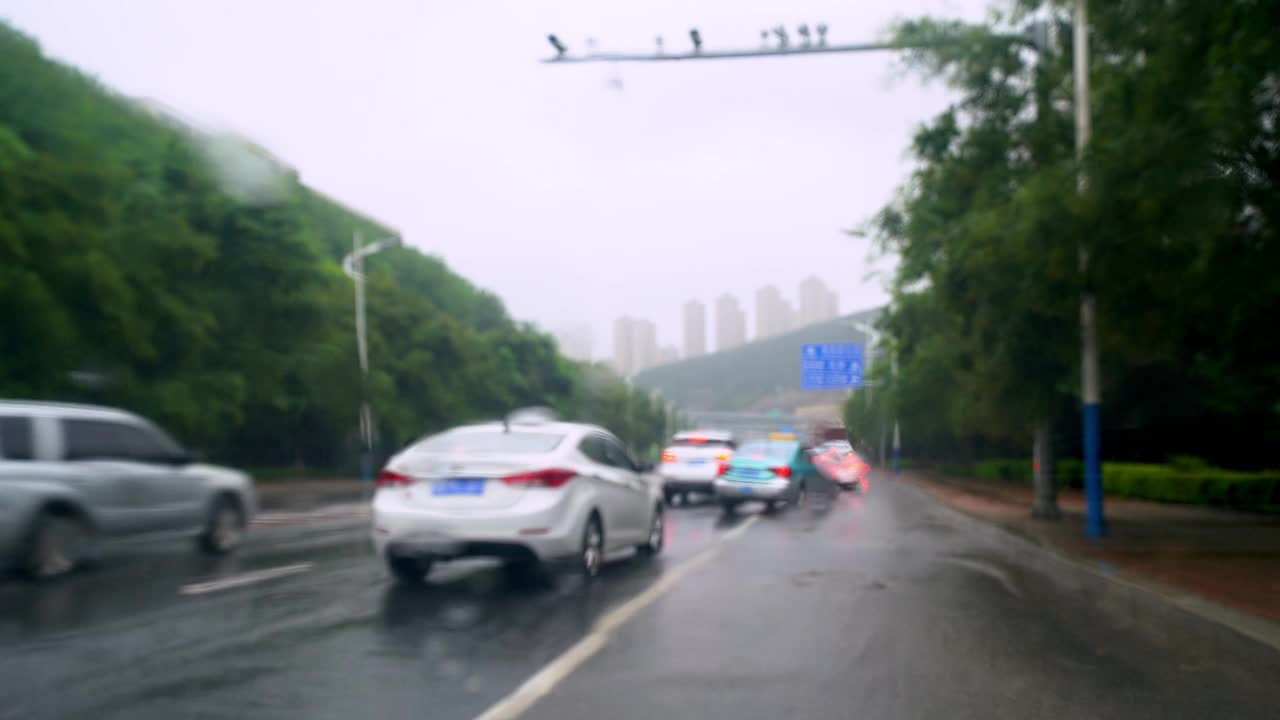 大连市的交通堵塞透过雨点覆盖的挡风玻璃模糊可见。视频素材