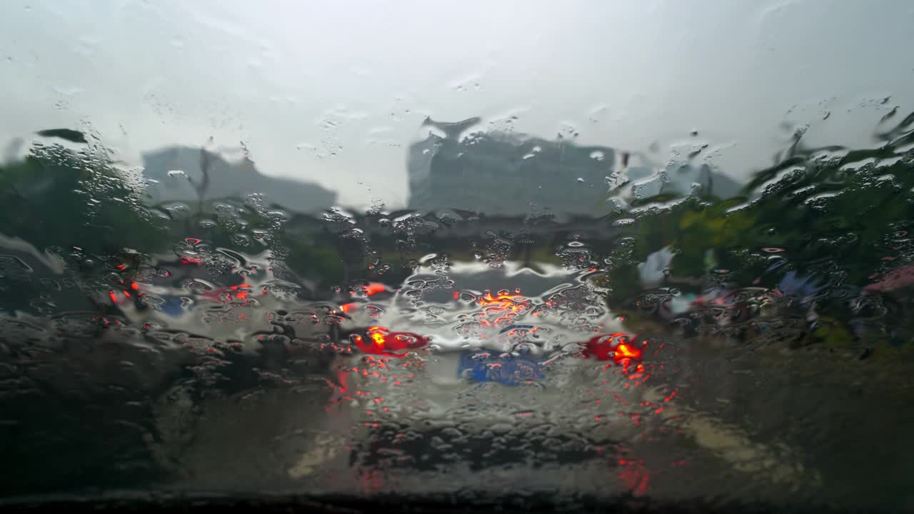 大连市的交通堵塞透过雨点覆盖的挡风玻璃模糊可见。视频素材