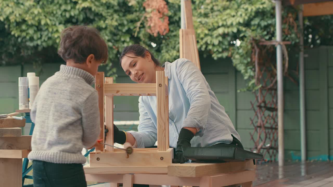 一个年轻女人和她可爱的儿子在家里做一个木制项目视频下载