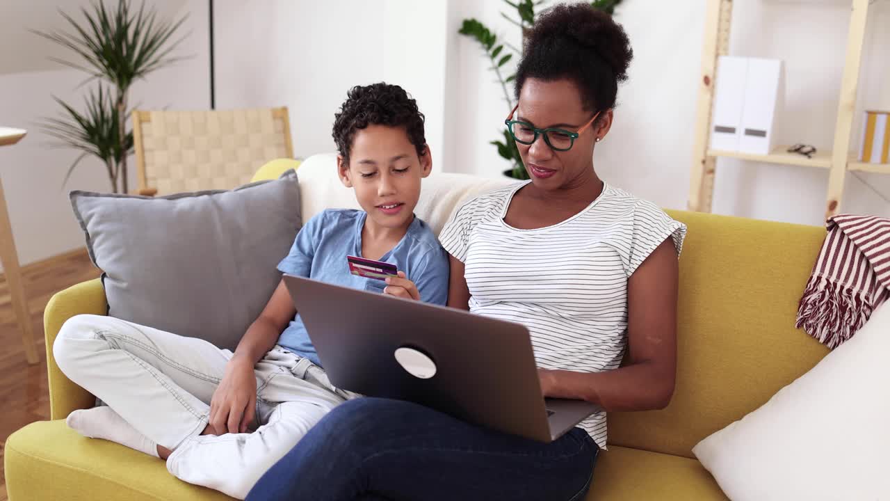非洲裔美国妇女管理她的财务，同时享受与她的儿子在沙发上视频下载