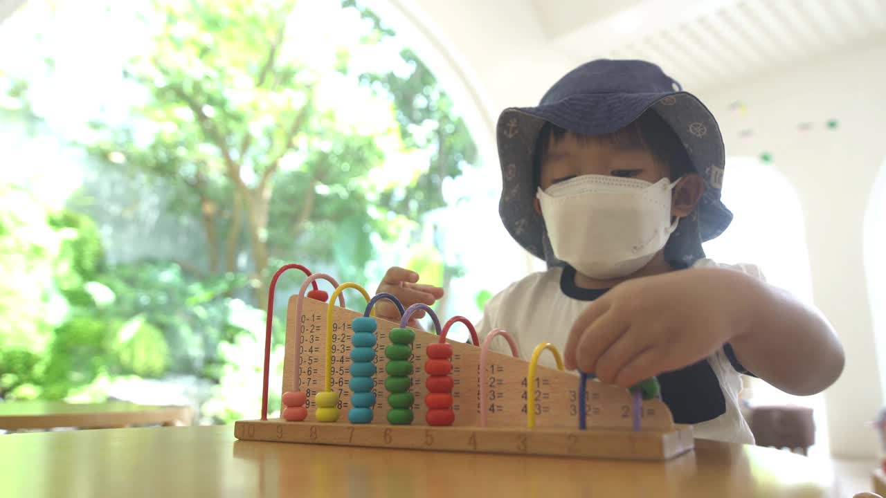 小男孩在游戏室里玩算盘学习数学的玩具视频素材