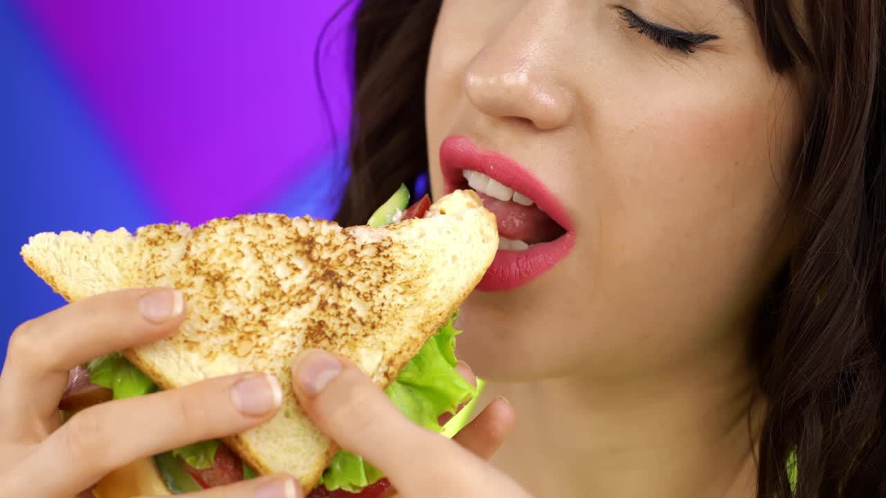 一个深色头发的女孩吃三明治当午餐。视频素材
