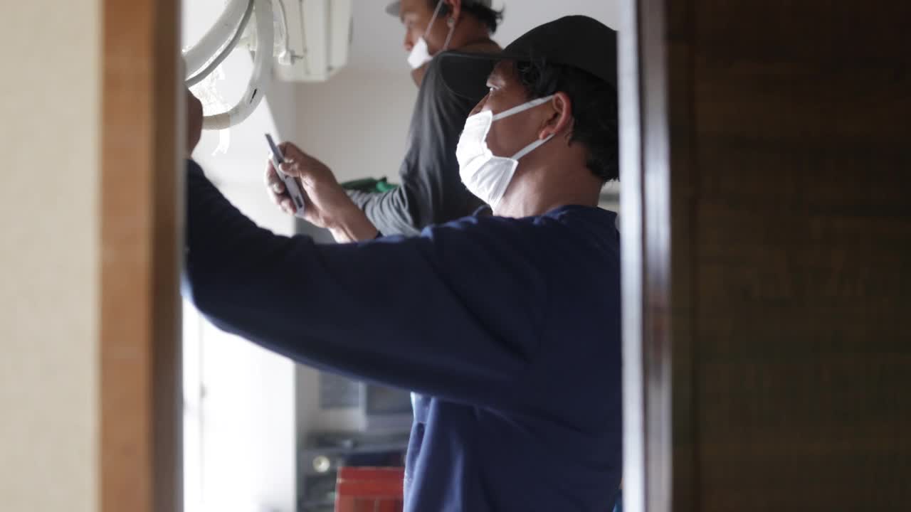 亚洲搬家人员在客厅拆除空调视频下载