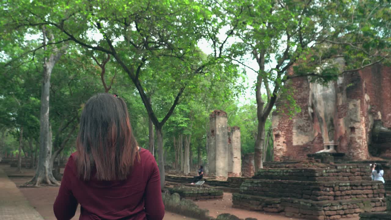 一名年轻的泰国女子带着纸地图在著名的甘蓬寺与一群游客一起探索历史时刻视频素材