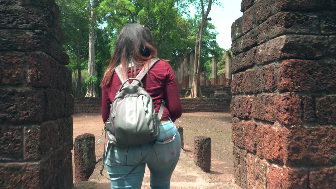 年轻的泰国女子和小袋纸地图探索历史时刻在著名的古老甘榜Phet寺庙，背面的视图视频素材