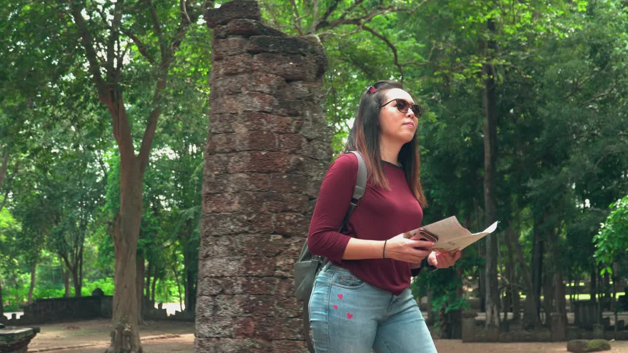 年轻的泰国女子和小袋纸地图探索历史时刻在著名的古老甘榜Phet寺庙，前面的视图视频素材