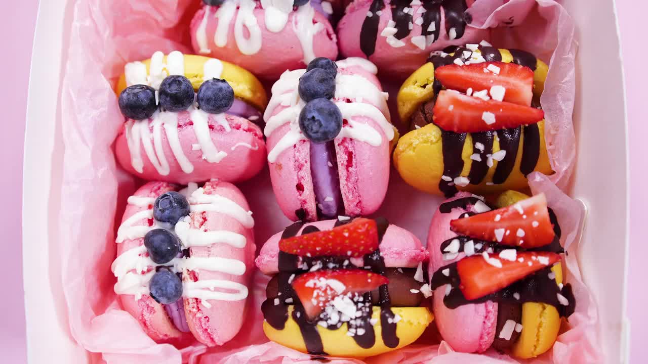 盒子里的马卡龙，手工制作的精美甜品，用巧克力装饰的新鲜草莓和蓝莓甜点，精致的黄色和粉色蛋糕，糖和健康食品视频下载