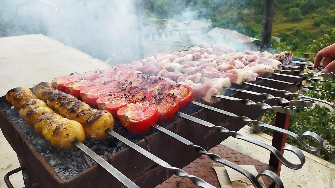厨师在村里准备烤肉。猪肉着火了。火上烤着红番茄、黄肉饼和猪肉。厨师送来的飞行盘视频下载