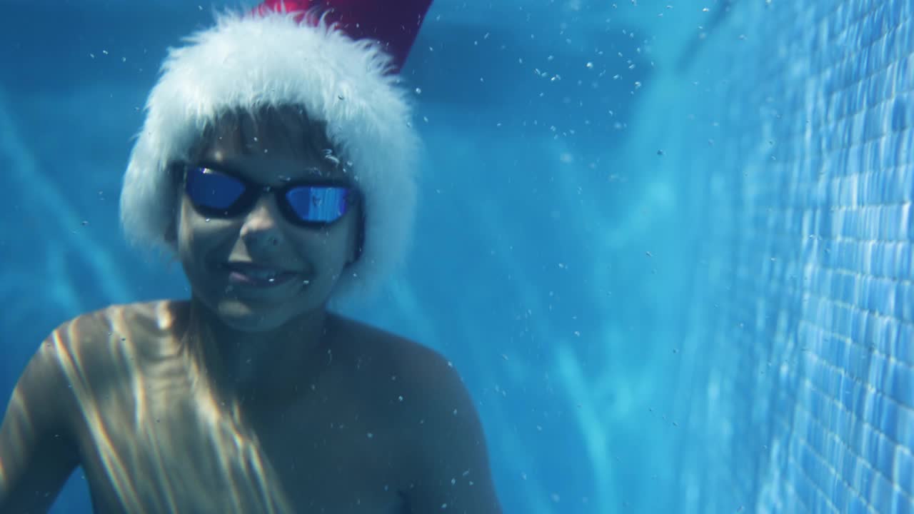 夏天的圣诞节，十几岁的男孩在游泳池里游泳视频素材