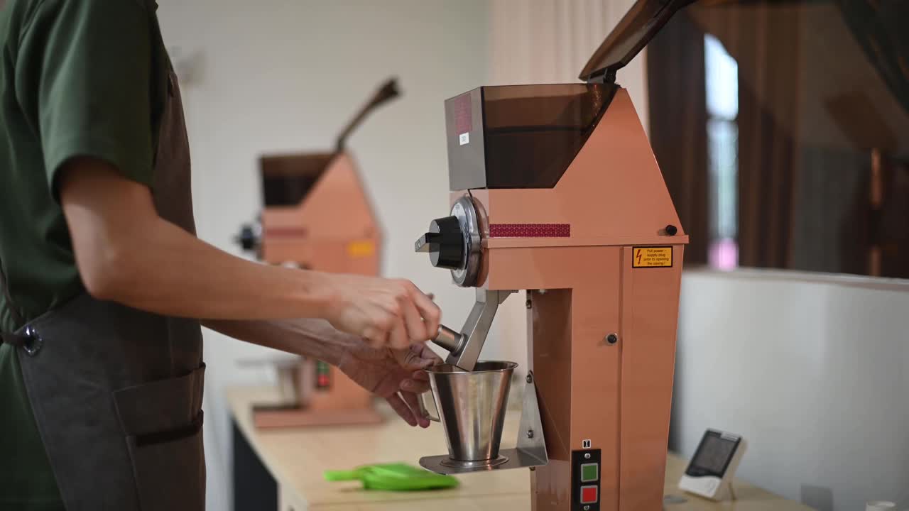 亚洲华人男性咖啡师正在研磨咖啡，准备泡制咖啡视频素材