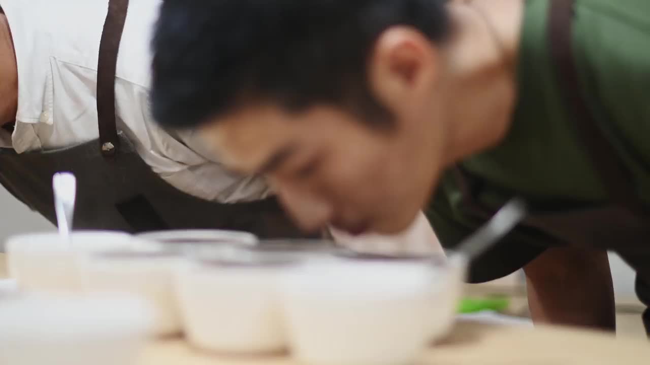 专业的亚洲华人男性咖啡师正在进行拔杯，弯下腰仔细闻每一个咖啡样品视频素材