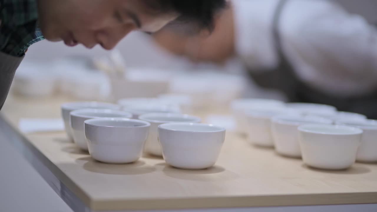 3名亚洲华裔男咖啡师品酒师表演杯咖啡，品尝杯咖啡后在剪贴板上写下视频素材